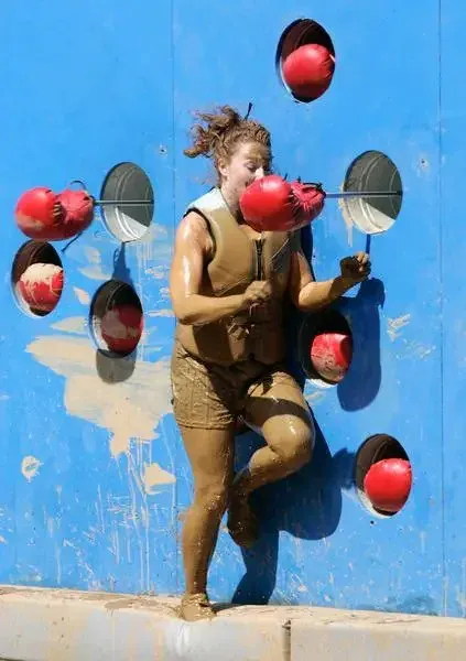 Contestant navigating a boxing-glove obstacle course wall
