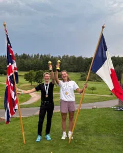 Two women speedgolfers holding national flags on a golf course
