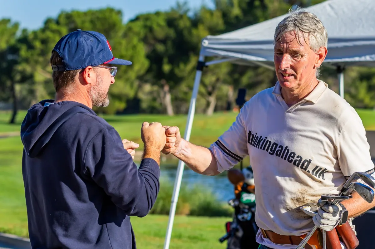 Two speedgolfers exchange a fist bump beside the course after a round.