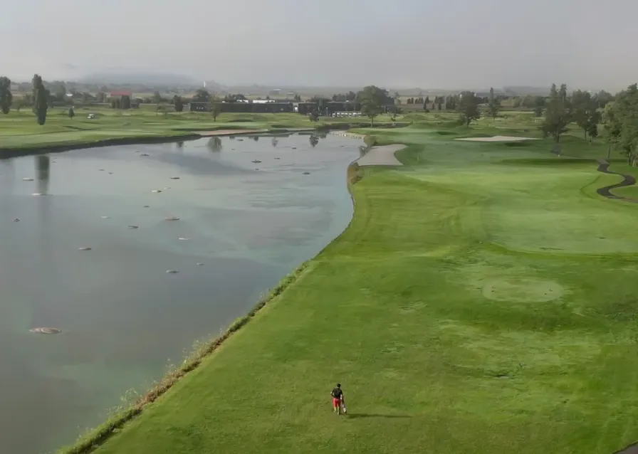 A golfer walks beside a large water hazard at Golf5 Country Bibai in Hokkaido.