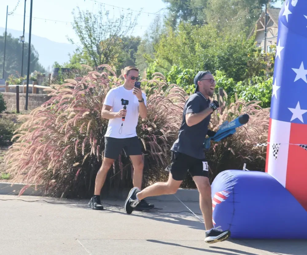 A speedgolfer runs through the U.S. Open finish area while another person films.